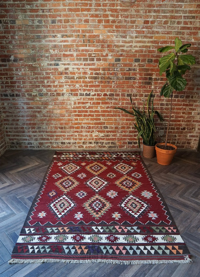 8 by 5 foot large red Turkish kilim area rug featuring large diamond medallions in the center and multiple striped borders around the outside