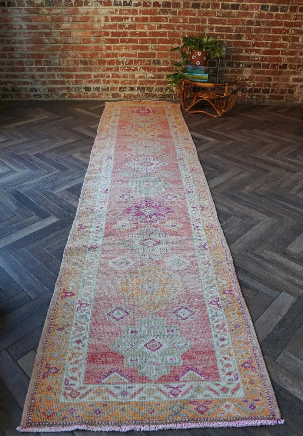 12 feet by 3 ft pink Turkish runner with beautiful large medallions down the center and pops of orange, sand, and dark pink throughout.