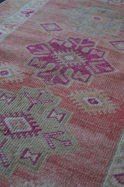 12 feet by 3 ft pink Turkish runner with beautiful large medallions down the center and pops of orange, sand, and dark pink throughout.