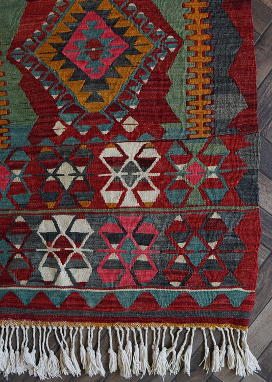 5.5 by 2.9 foot colorful Turkish area rug featuring diamond geometric patterns and bright accent colors