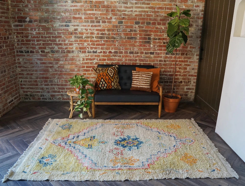 Large high pile Turkish area rug measuring 8 by 5, very muted yellow and cream coloring with pops of blue and orange, perfect for a living room room or bedroom space, unique, one-of-a-kind