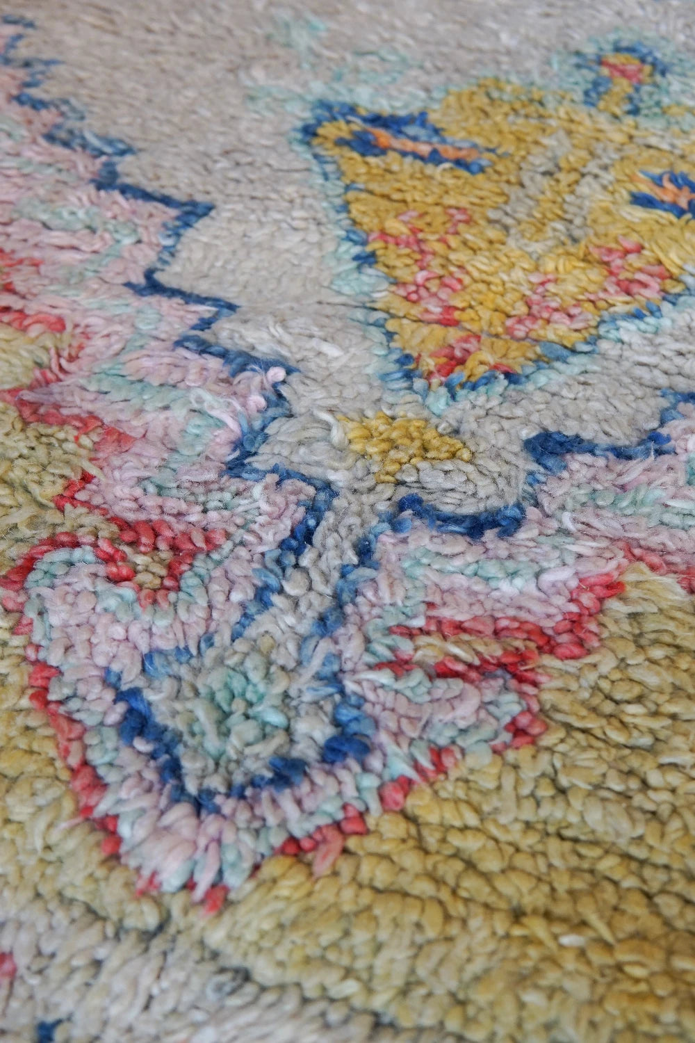 Large high pile Turkish area rug measuring 8 by 5, very muted yellow and cream coloring with pops of blue and orange, perfect for a living room room or bedroom space, unique, one-of-a-kind