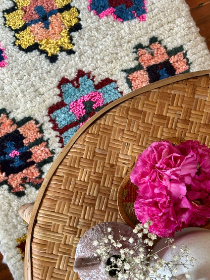 Wicker table with pink flowers on a patterned rug