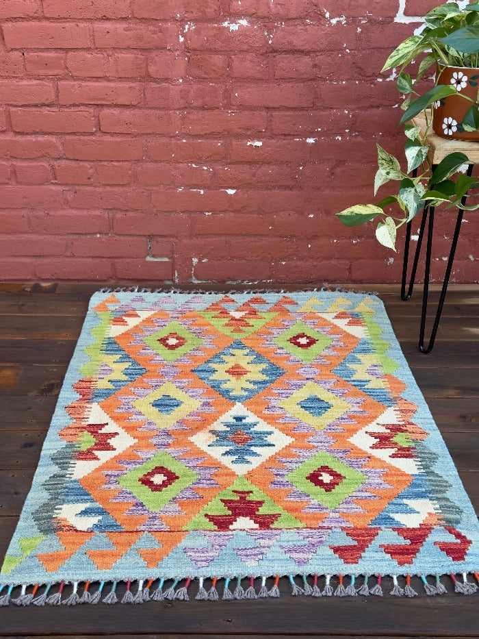 3.5 foot by 2.5 foot small kilim mini rug featuring a multicolored rainbow diamond pattern 