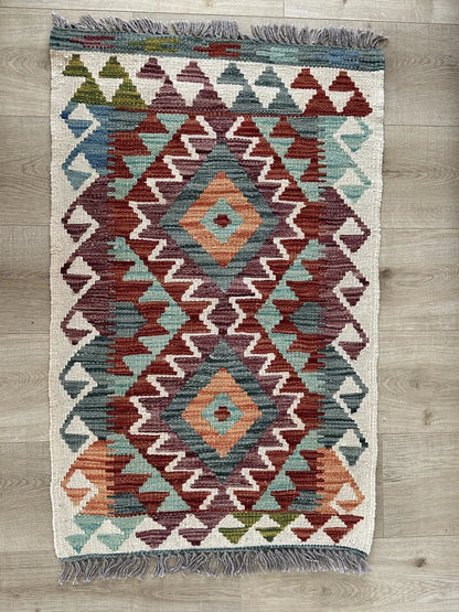 mini colorful Turkish rug featuring pops of red, orange green and blue and geometric diamond pattern throughout