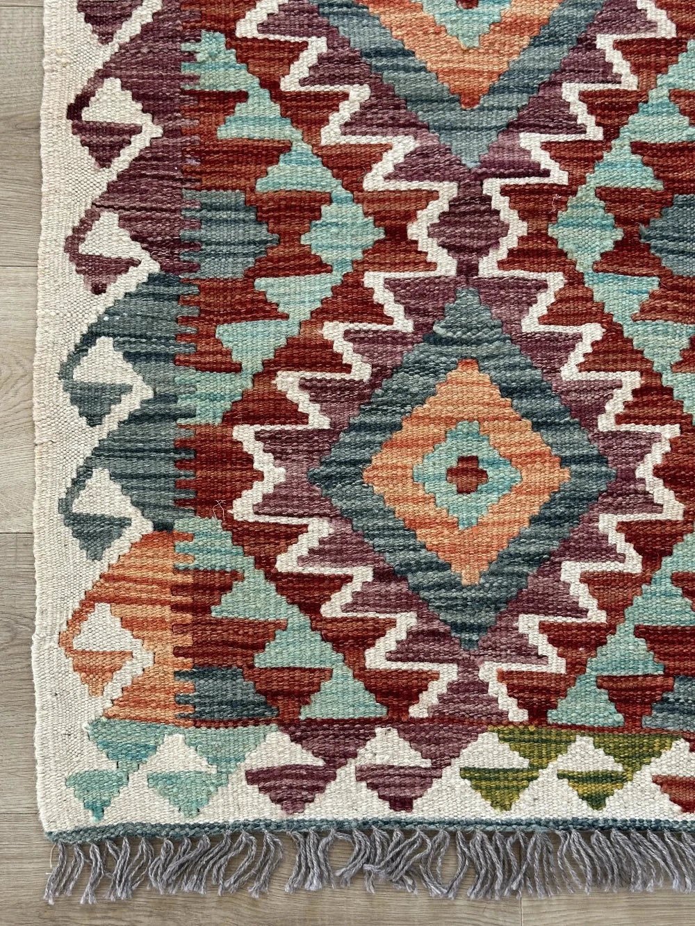 mini colorful Turkish rug featuring pops of red, orange green and blue and geometric diamond pattern throughout