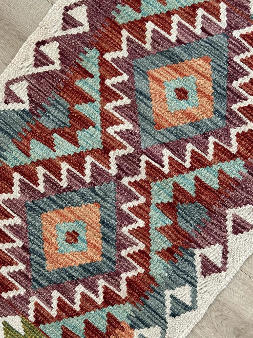 mini colorful Turkish rug featuring pops of red, orange green and blue and geometric diamond pattern throughout