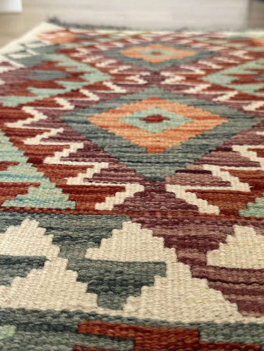 mini colorful Turkish rug featuring pops of red, orange green and blue and geometric diamond pattern throughout