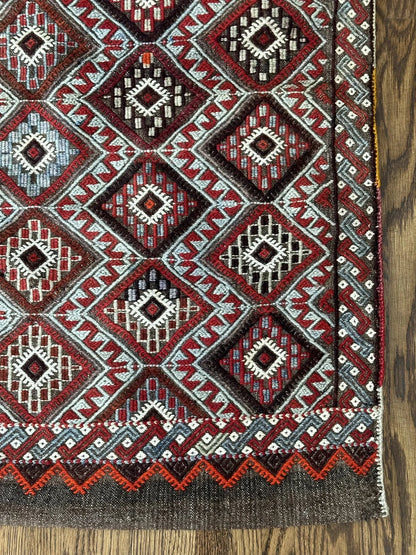 Mini Turkish Rug featuring pops of red and light blue with a repeating diamond pattern throughout