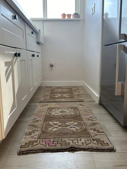 Handmade neutral Turkish mini rug featuring sand, brown and pops of pink and blue with geometric patterns around the border