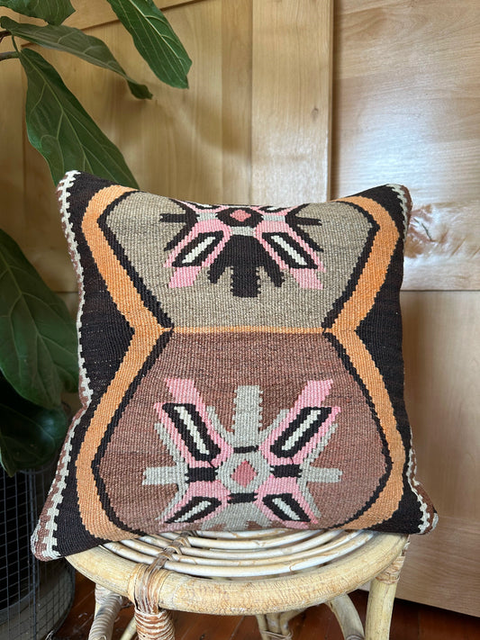 Handwoven earthy brown Turkish throw pillow, 16x16 inches, wool front with geometric design and pops of pink and faded orange, cotton backing—boho home decor.