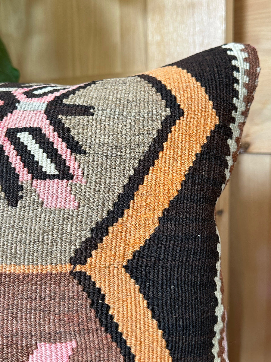 Handwoven earthy brown Turkish throw pillow, 16x16 inches, wool front with geometric design and pops of pink and faded orange, cotton backing—boho home decor.