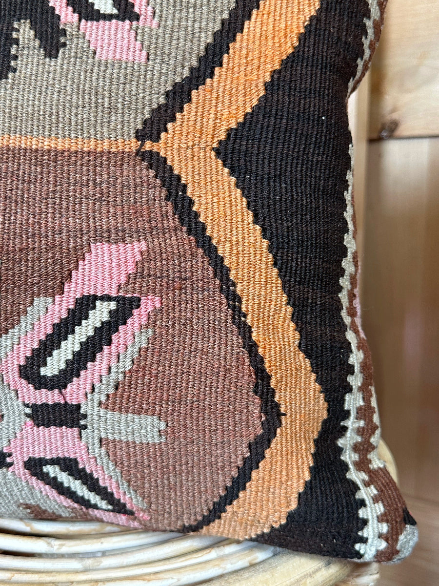 Handwoven earthy brown Turkish throw pillow, 16x16 inches, wool front with geometric design and pops of pink and faded orange, cotton backing—boho home decor.