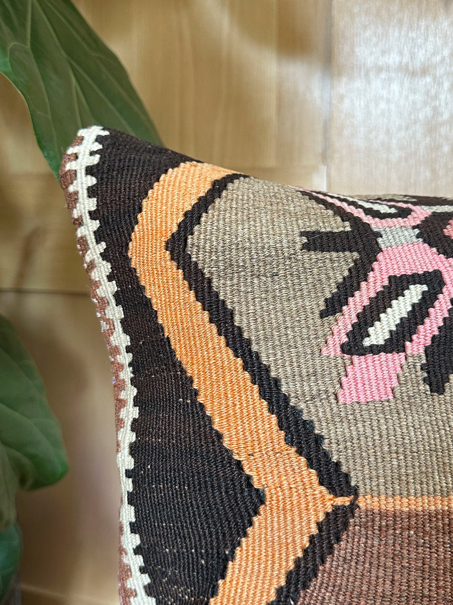 Handwoven earthy brown Turkish throw pillow, 16x16 inches, wool front with geometric design and pops of pink and faded orange, cotton backing—boho home decor.