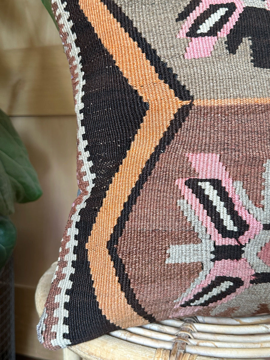 Handwoven earthy brown Turkish throw pillow, 16x16 inches, wool front with geometric design and pops of pink and faded orange, cotton backing—boho home decor.