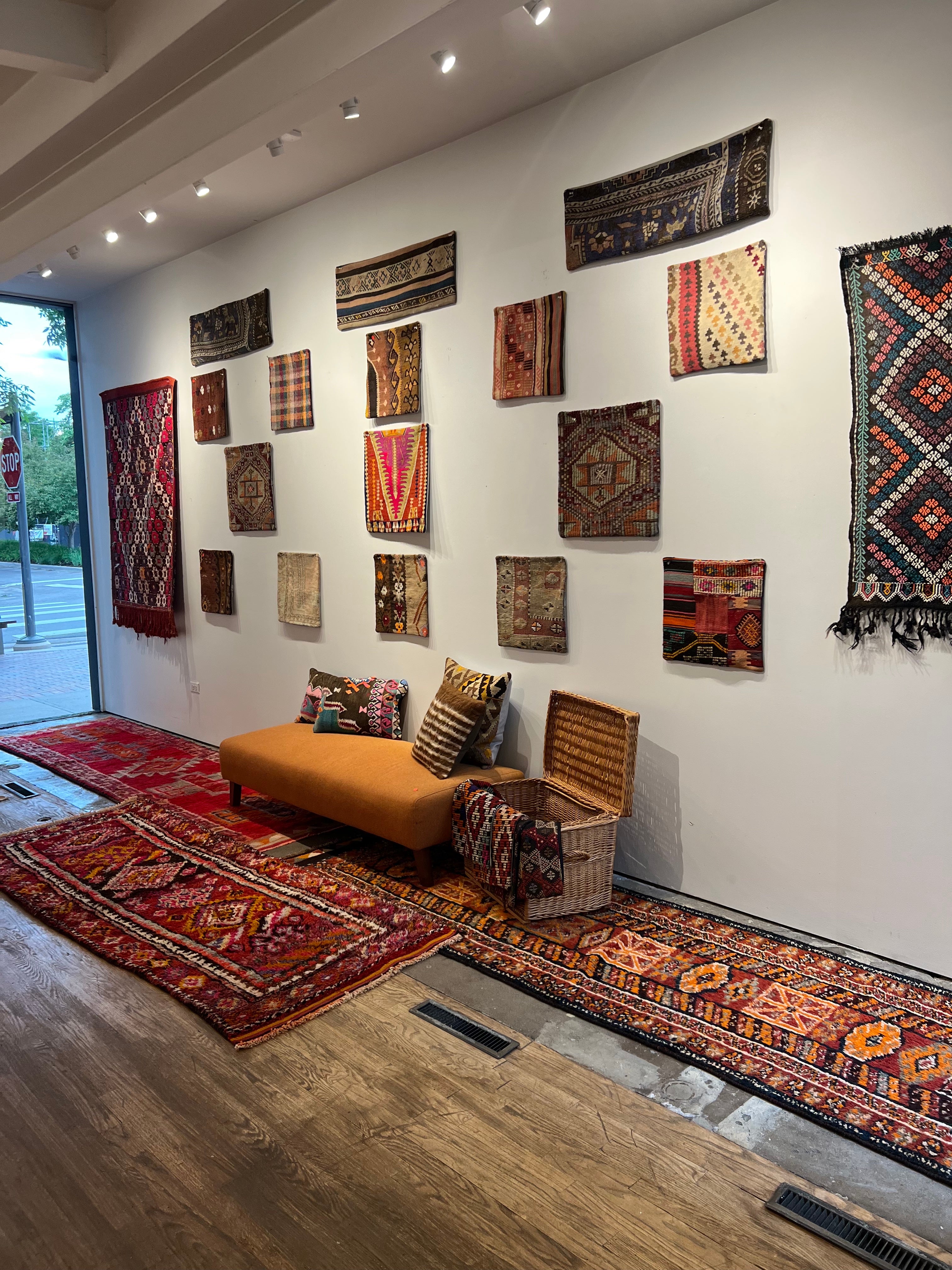 colorful Turkish rugs displayed in a gallery featuring dozens of colorful turkish pillows hung up on a wall