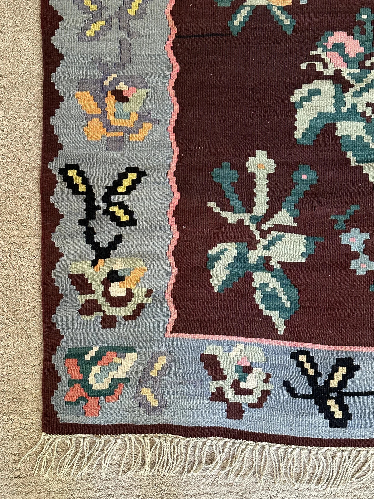 Large handmade rug featuring a sky blue floral border and a coffee brown inner field with large floral design