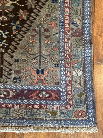 Large vintage Turkish rug featuring floral and geometric designs with hues of navy, robin eggs blue, olive, mauve and taupe.