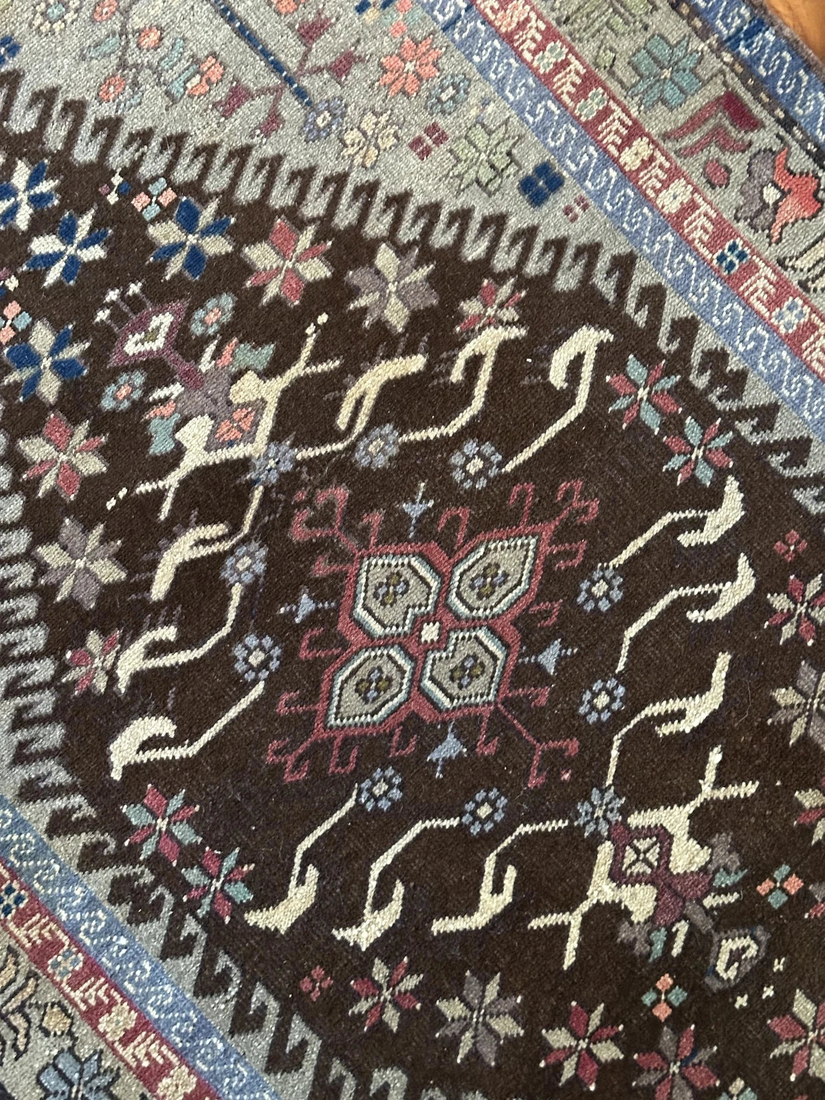 Large vintage Turkish rug featuring floral and geometric designs with hues of navy, robin eggs blue, olive, mauve and taupe.