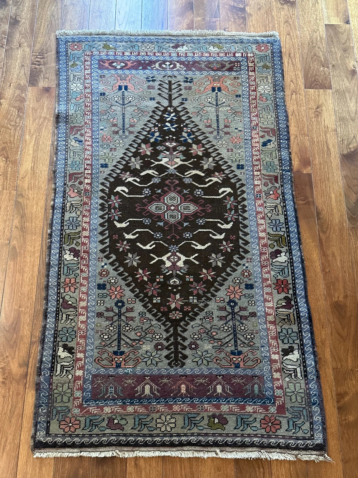 Large vintage Turkish rug featuring floral and geometric designs with hues of navy, robin eggs blue, olive, mauve and taupe.