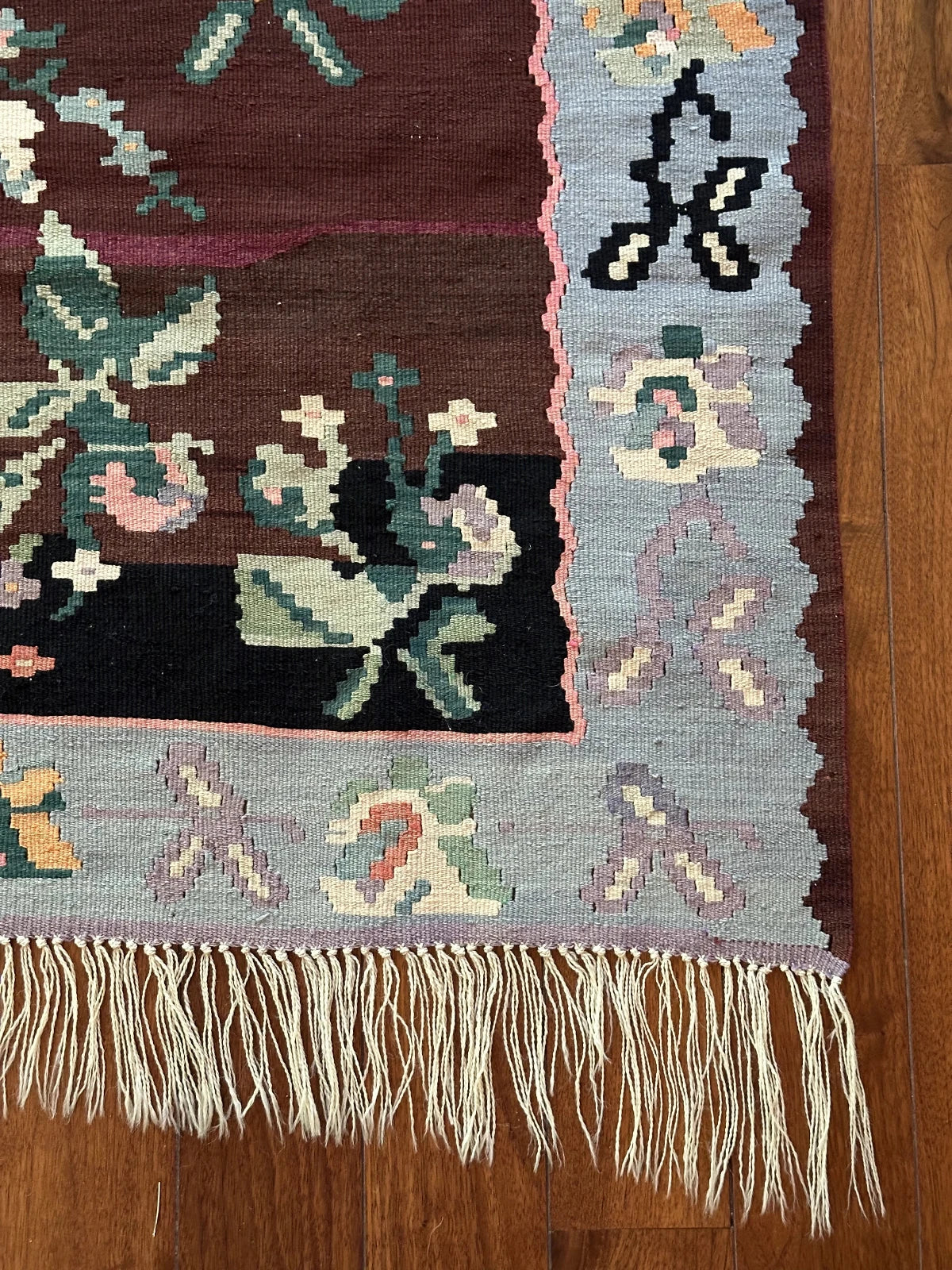 Large handmade rug featuring a sky blue floral border and a coffee brown inner field with large floral design