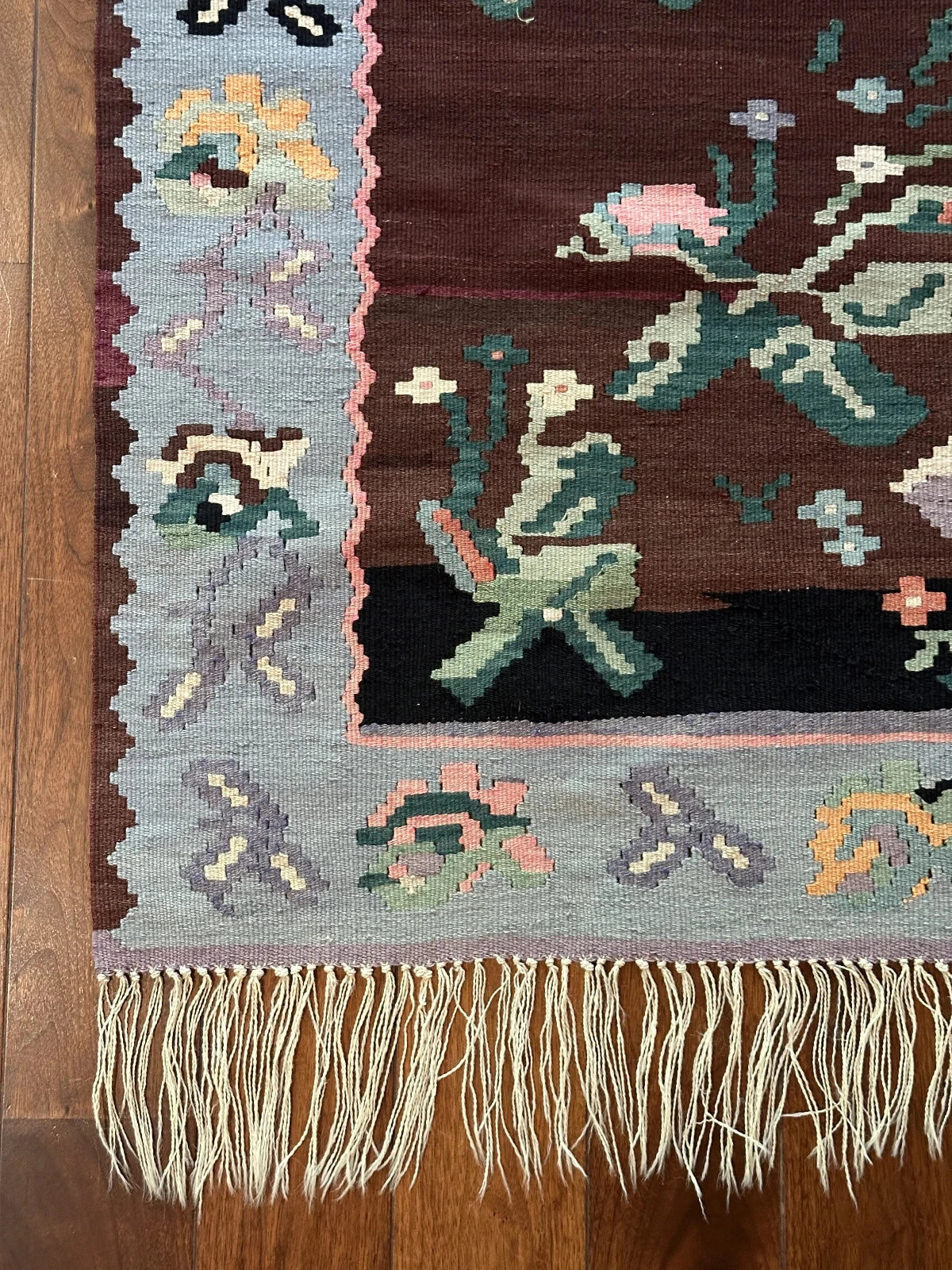 Large handmade rug featuring a sky blue floral border and a coffee brown inner field with large floral design