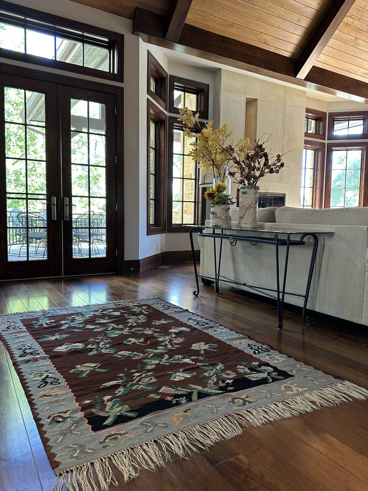 Large handmade rug featuring a sky blue floral border and a coffee brown inner field with large floral design