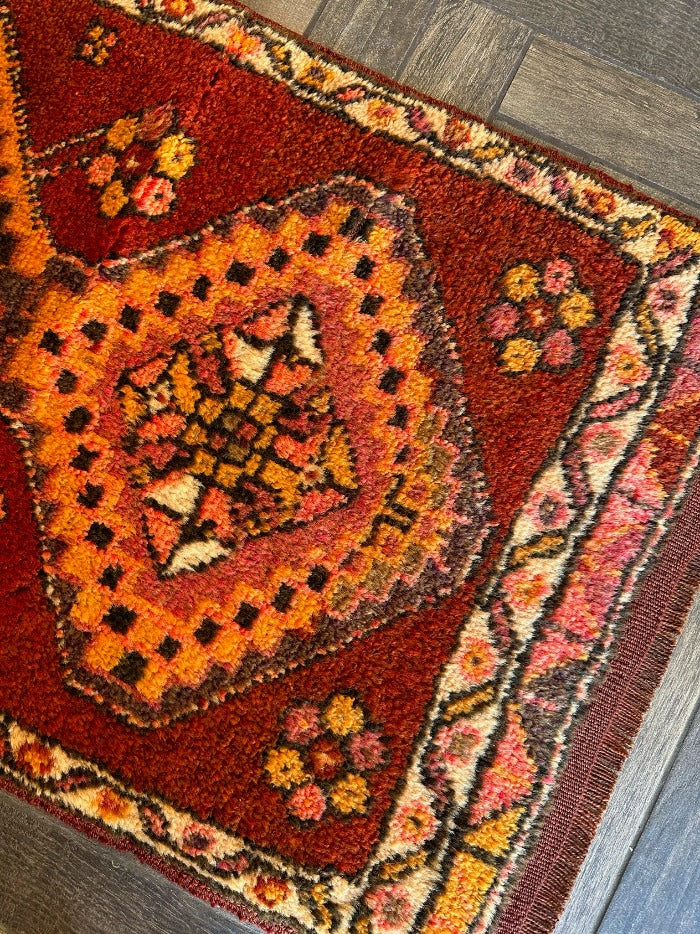 3 by 2 small Turkish area rug featuring sunset orange, red and pink coloring and two large medallions on the center with flowers around