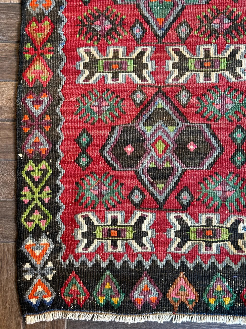 4.5 foot by 2 foot small Turkish kilim runner featuring a black border and geometric patterns throughout in jewel tones