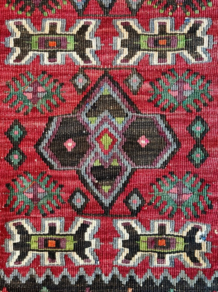 4.5 foot by 2 foot small Turkish kilim runner featuring a black border and geometric patterns throughout in jewel tones