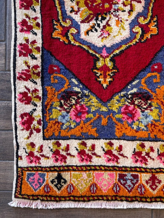 2 x 4 small floral Turkish area rug featuring rose and other floral patterns and deep red hues with bright pops of orange pink blue and green.