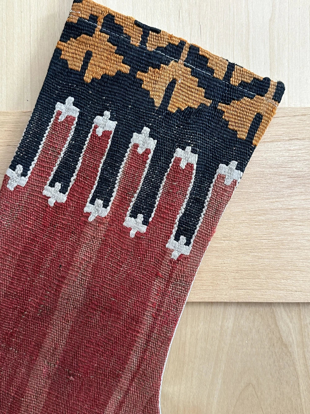 handmade Turkish Christmas stocking featuring a solid red body and a black and orange geometric top