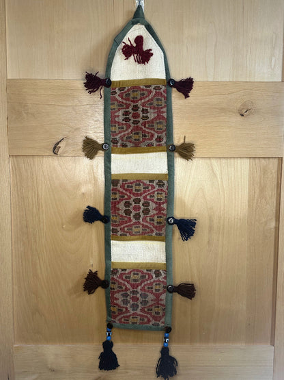 Handmade decorative Turkish rug wall organizer with pink geometric designs, 3 pockets, tassels, and an evil eye charm. Upcycled vintage textile art by High Pile Designs.