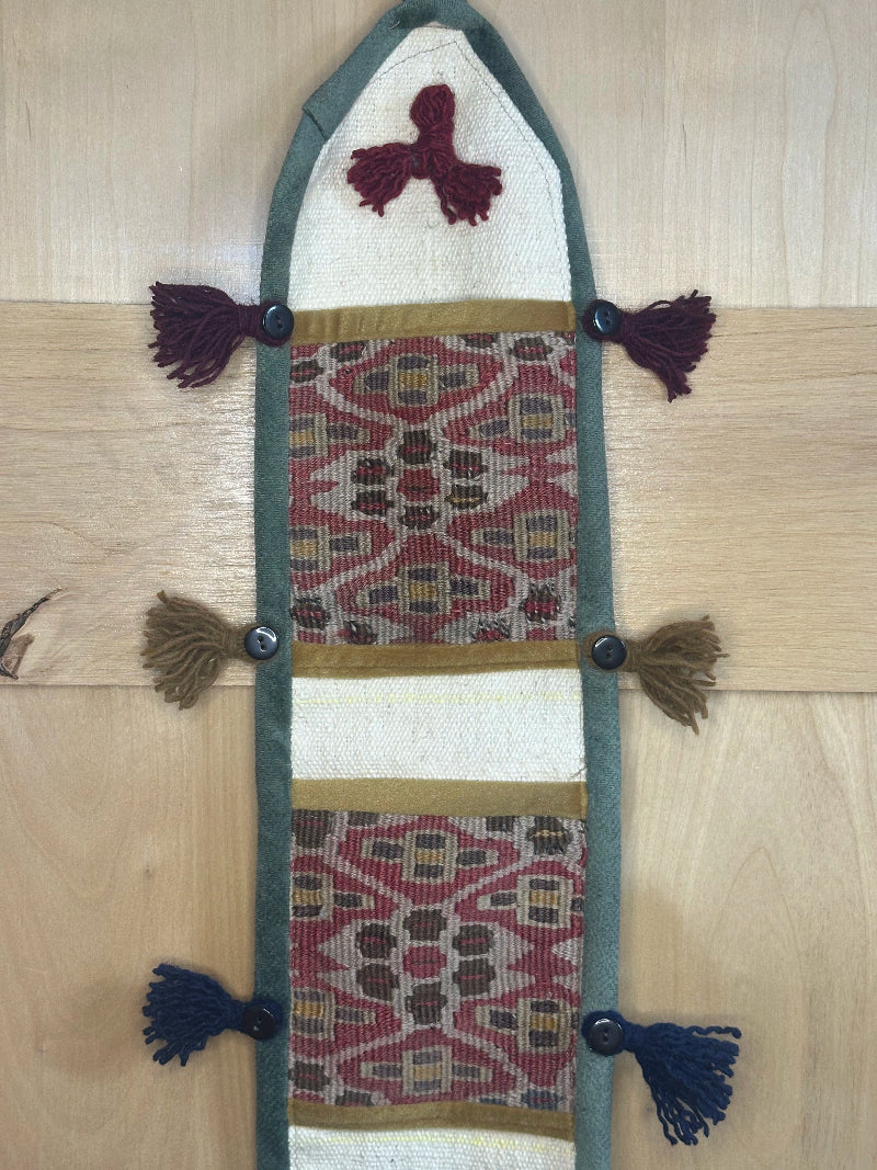 Handmade decorative Turkish rug wall organizer with pink geometric designs, 3 pockets, tassels, and an evil eye charm. Upcycled vintage textile art by High Pile Designs.