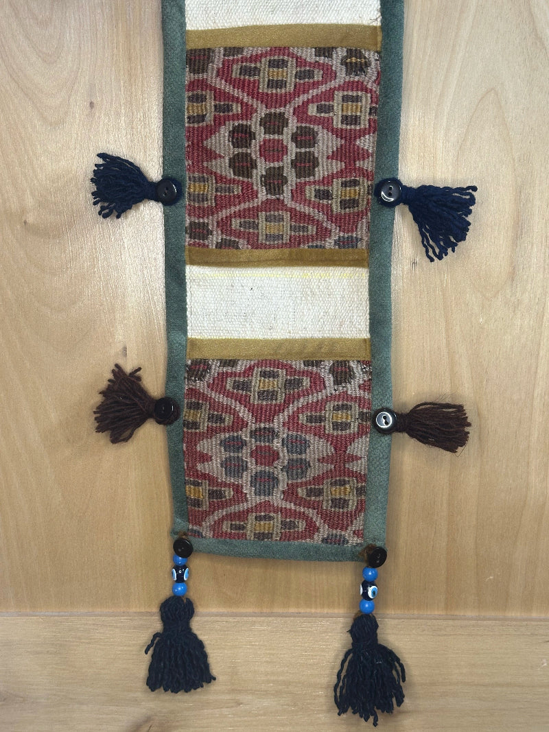 Handmade decorative Turkish rug wall organizer with pink geometric designs, 3 pockets, tassels, and an evil eye charm. Upcycled vintage textile art by High Pile Designs.