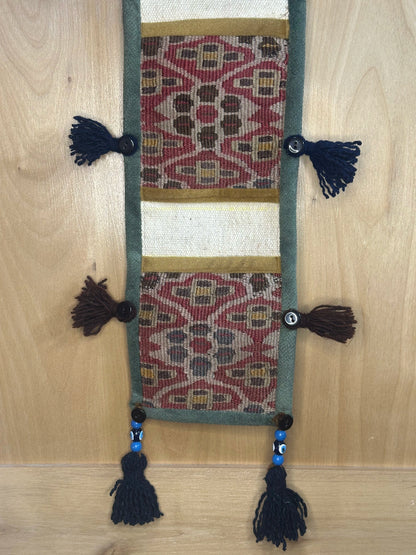 Handmade decorative Turkish rug wall organizer with pink geometric designs, 3 pockets, tassels, and an evil eye charm. Upcycled vintage textile art by High Pile Designs.