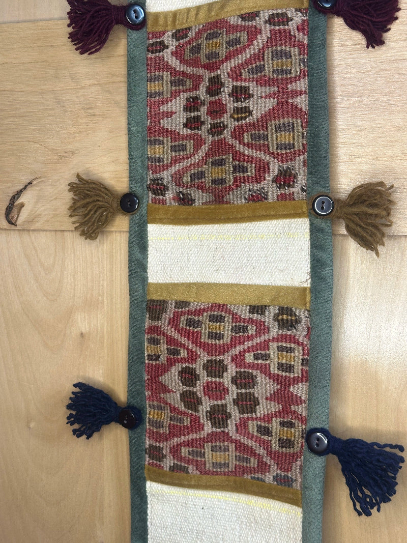 Handmade decorative Turkish rug wall organizer with pink geometric designs, 3 pockets, tassels, and an evil eye charm. Upcycled vintage textile art by High Pile Designs.