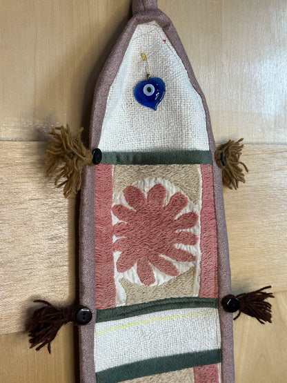 Handmade Turkish rug wall hanging with pink floral designs, 3 pockets, tassels, and evil eye charm. Upcycled vintage textile art by High Pile Designs.