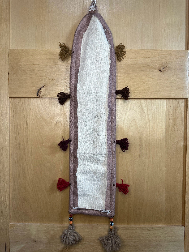 Handmade Turkish rug wall hanging with pink floral designs, tassels, and an evil eye charm. Upcycled vintage textile art by High Pile Designs.