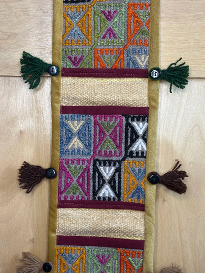 Handmade Turkish rug wall hanging with geometric designs, 3 pockets, tassels, and an evil eye charm. Upcycled vintage textile art by High Pile Designs.