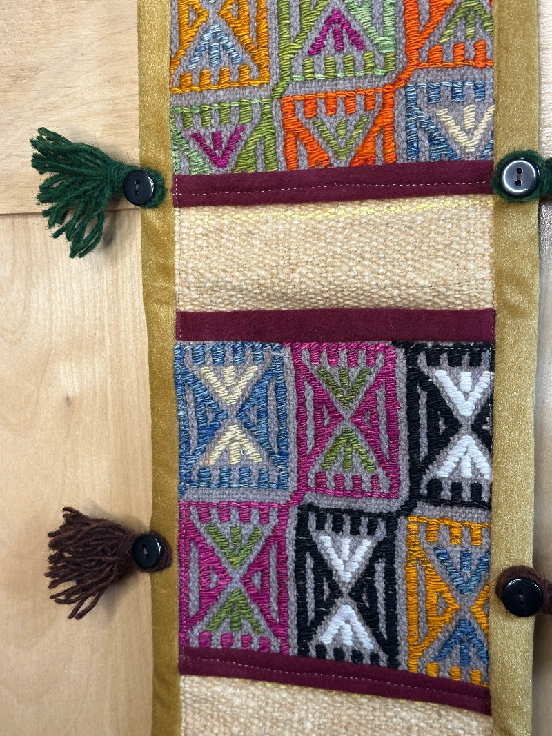 Handmade Turkish rug wall hanging with geometric designs, 3 pockets, tassels, and an evil eye charm. Upcycled vintage textile art by High Pile Designs.