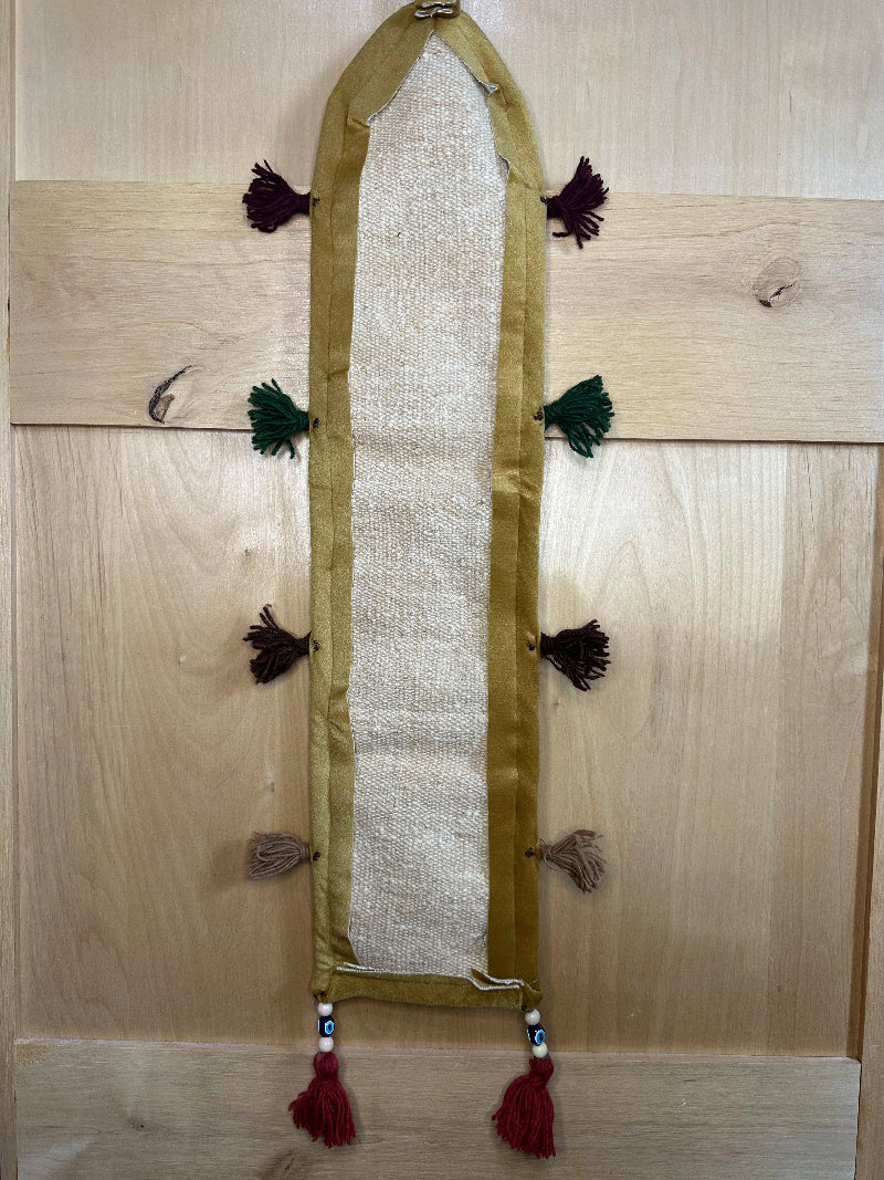 Handmade Turkish rug wall hanging with geometric designs, 3 pockets, tassels, and an evil eye charm. Upcycled vintage textile art by High Pile Designs.