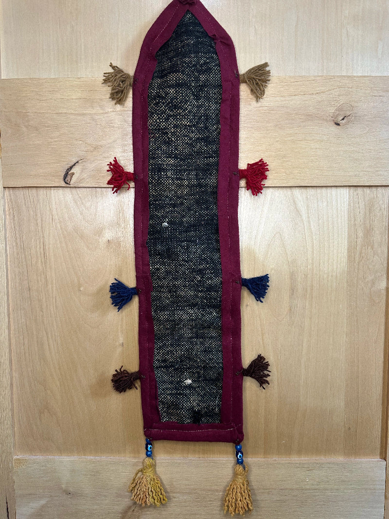 Handmade Turkish rug wall hanging with multicolor geometric designs, 3 pockets, tassels, and an evil eye charm. Upcycled vintage textile art by High Pile Designs.