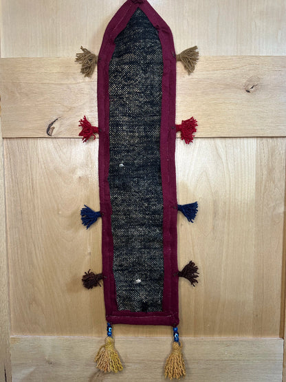 Handmade Turkish rug wall hanging with multicolor geometric designs, 3 pockets, tassels, and an evil eye charm. Upcycled vintage textile art by High Pile Designs.