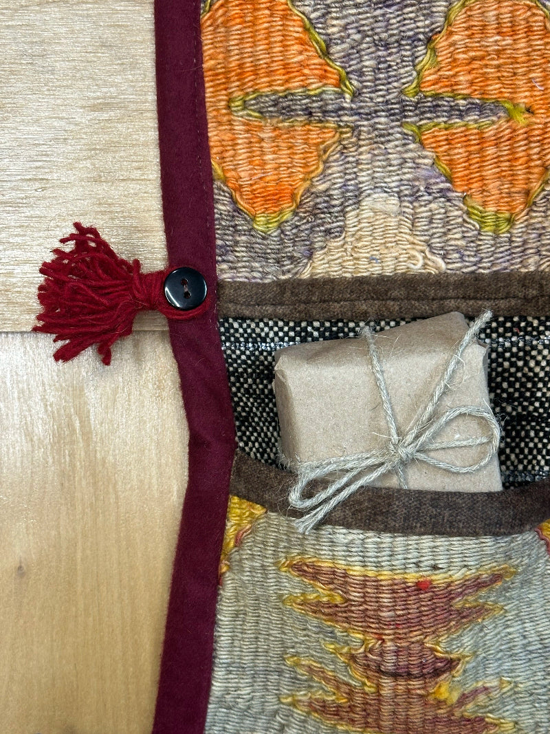 Detailed shot of handmade, decorative Turkish rug wall organizer with wrapped gift. Upcycled vintage textile art by High Pile Designs. 