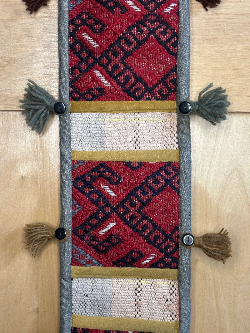 Handmade Turkish rug wall hanging with geometric designs, 3 pockets, tassels, and an evil eye charm. Upcycled vintage textile art by High Pile Designs.