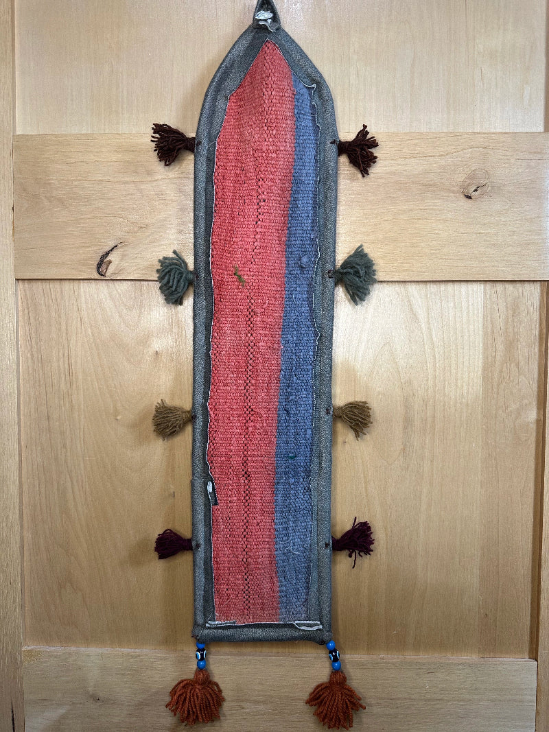 Handmade Turkish rug wall hanging with geometric designs, 3 pockets, tassels, and an evil eye charm. Upcycled vintage textile art by High Pile Designs.