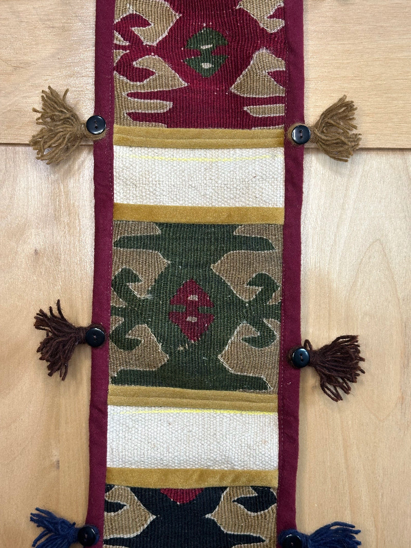Handmade Turkish rug wall hanging with geometric designs, tassels, and an evil eye charm. Upcycled vintage textile art by High Pile Designs.