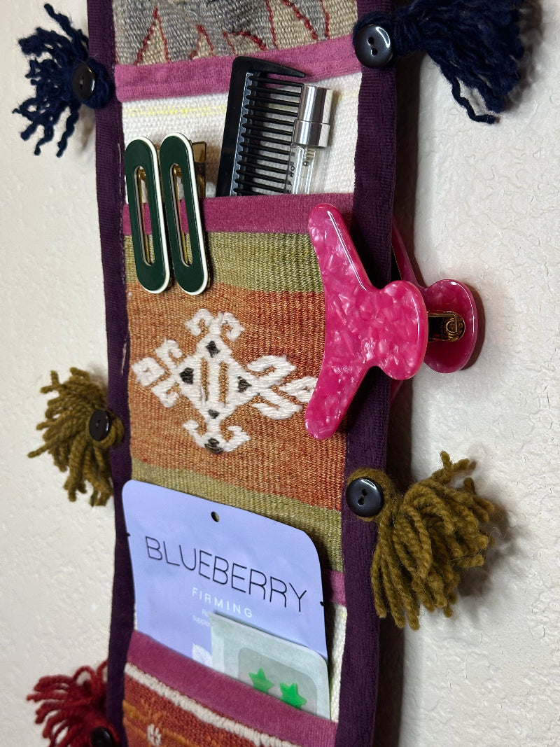 Handmade Turkish rug wall organizer storing bathroom & hair accessories. Upcycled vintage textile art by High Pile Designs.