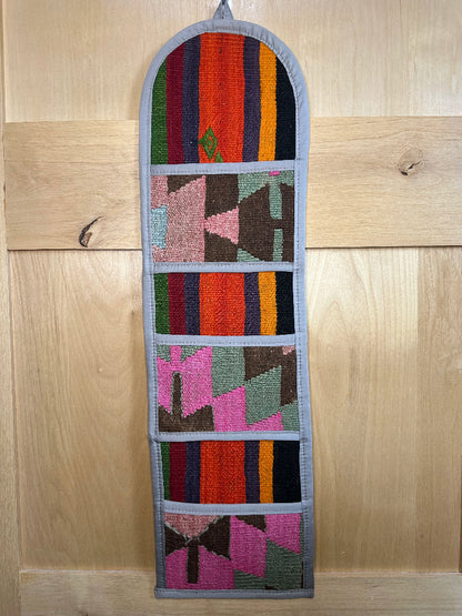 Decorative, handmade Turkish rug wall organizer with vibrant stripe designs and 3 storage pockets. Upcycled vintage textile art by High Pile Designs.
